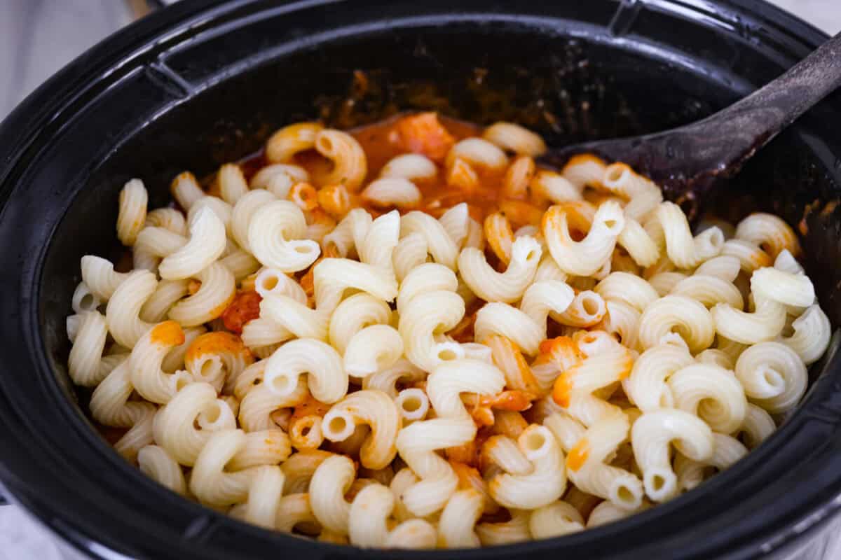 Cooked pasta added to the shredded chicken and pasta sauces in the crockpot. 
