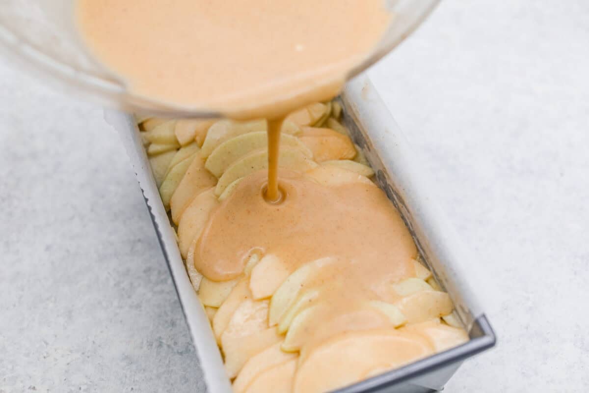 Pouring extra bater into the loaf pan with the apple mixture. 