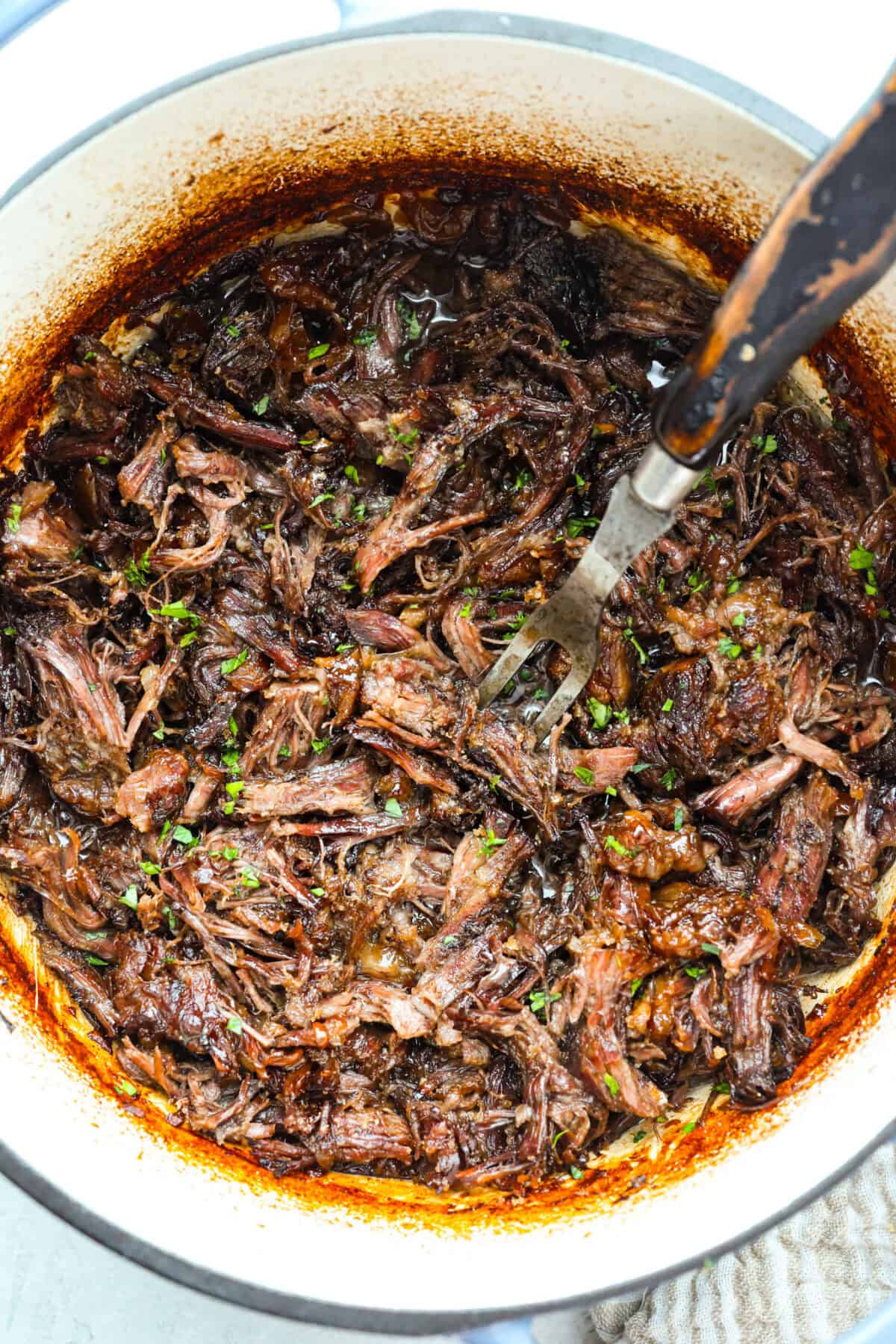 Overhead shot of caramelized chuck roast shredded and crispy from being broiled. 