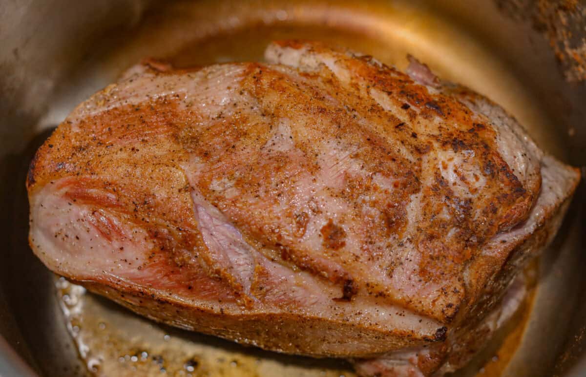 Pork shoulder being seared in the bottom of the pan. 