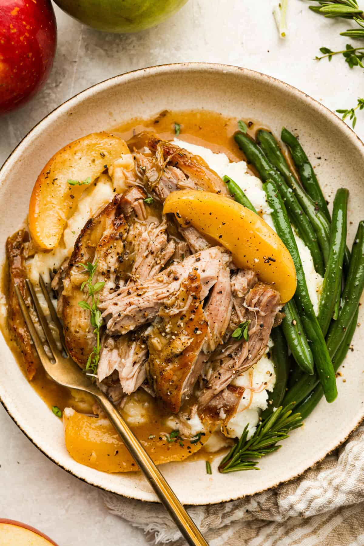 Serving size of apple cider pork roast over mashed potatoes and next to green beans.