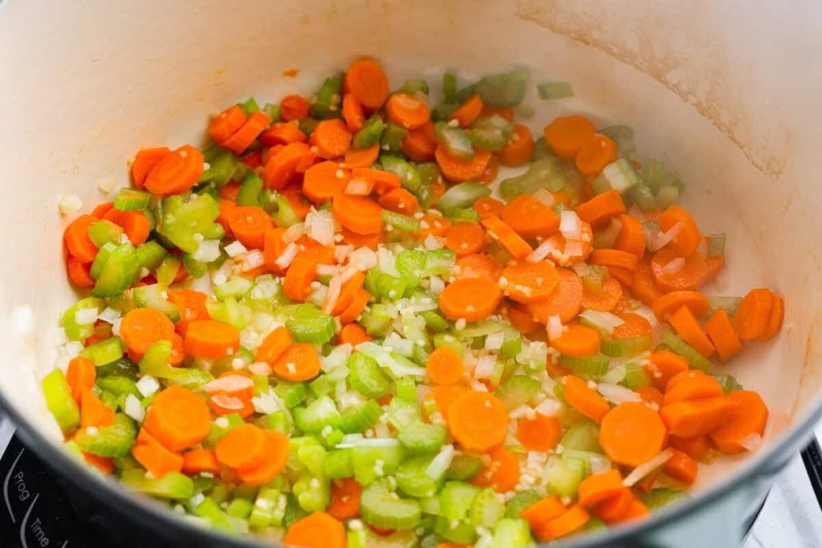 Carrots, onion, celery and garlic cooking in a pot. 