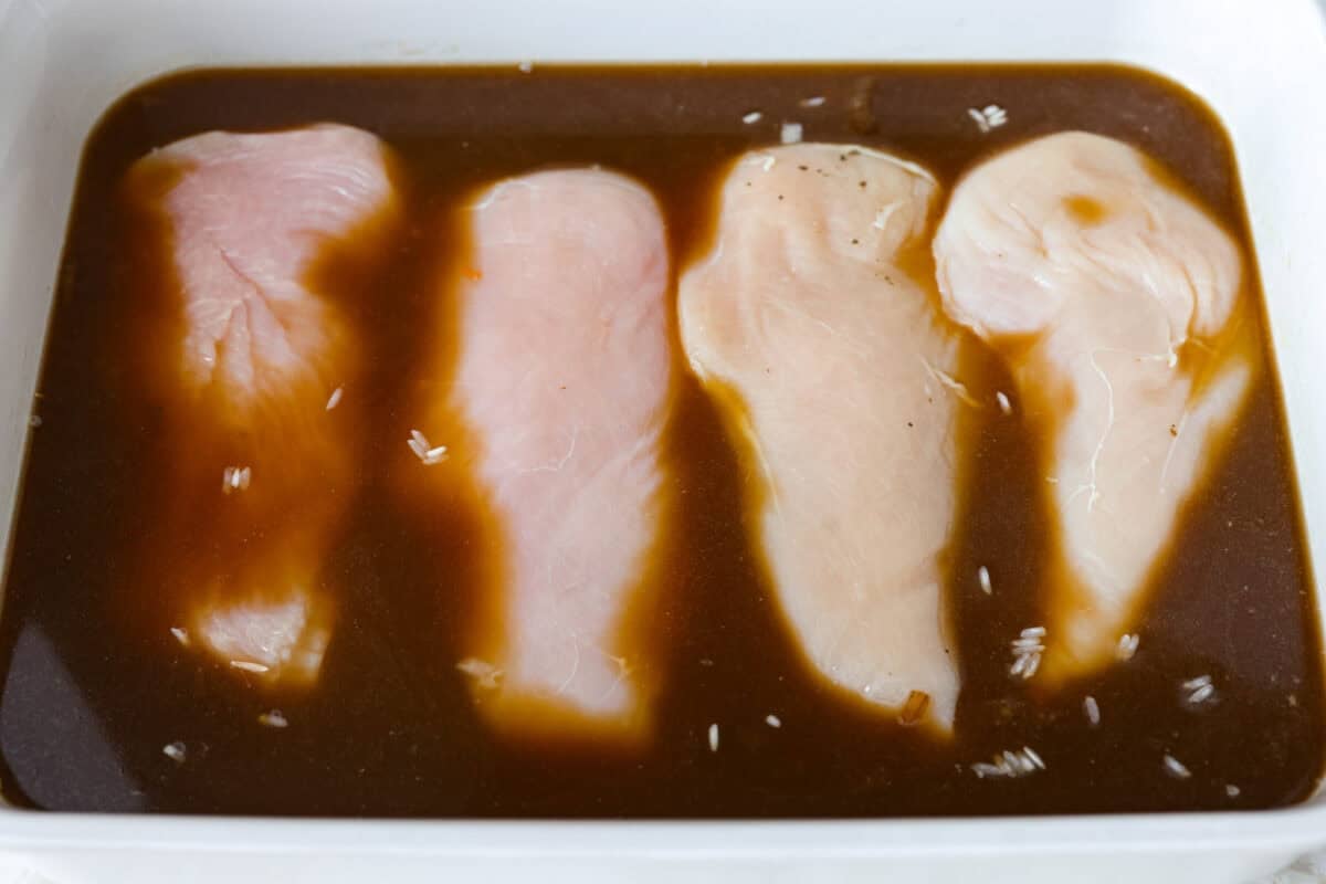 Chicken breasts added to the rice and broth mixture in the baking dish. 