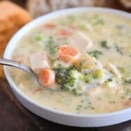 Soup bowl with creamy soup, chicken, broccoli, carrots, cheese, and chicken.