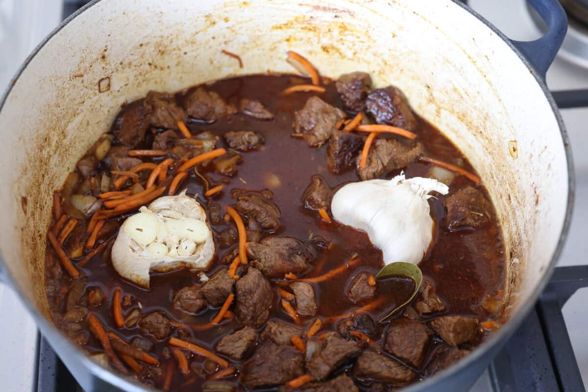 Beef broth and garlic heads added to the dutch oven. 