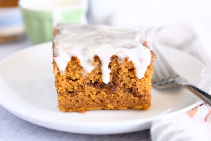 One square of glazed pumpkin cinnamon swirl cake on white plate.