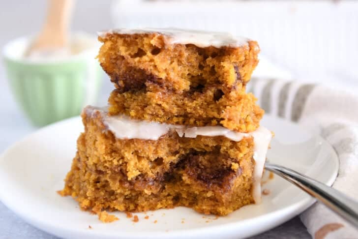 Two half slices of pumpkin cinnamon swirl cake stacked on top of each other on white plate.