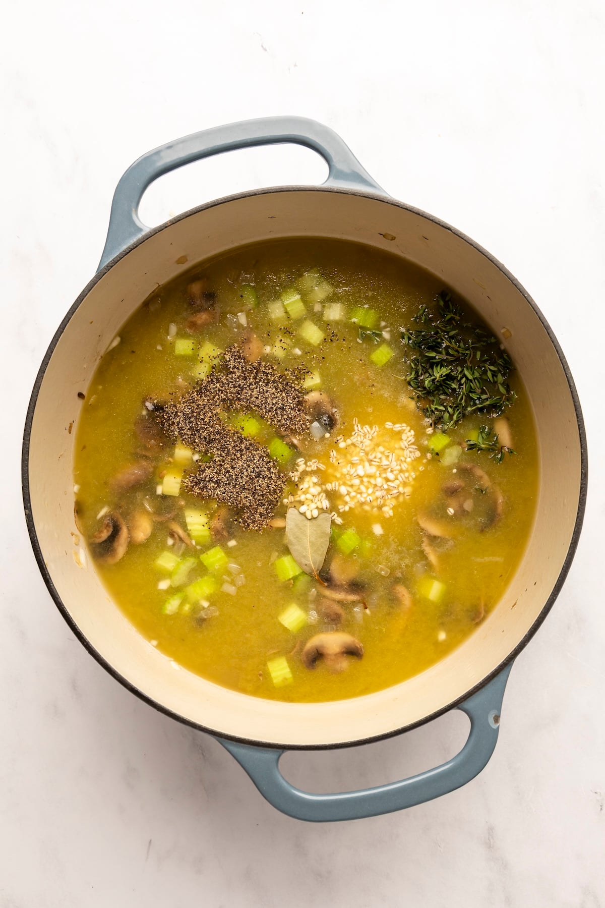 dutch oven with broth, tomato paste, soy sauce, salt, pepper, thyme, bay leaf, barley, mushroom soaking liquid, and dried mushrooms
