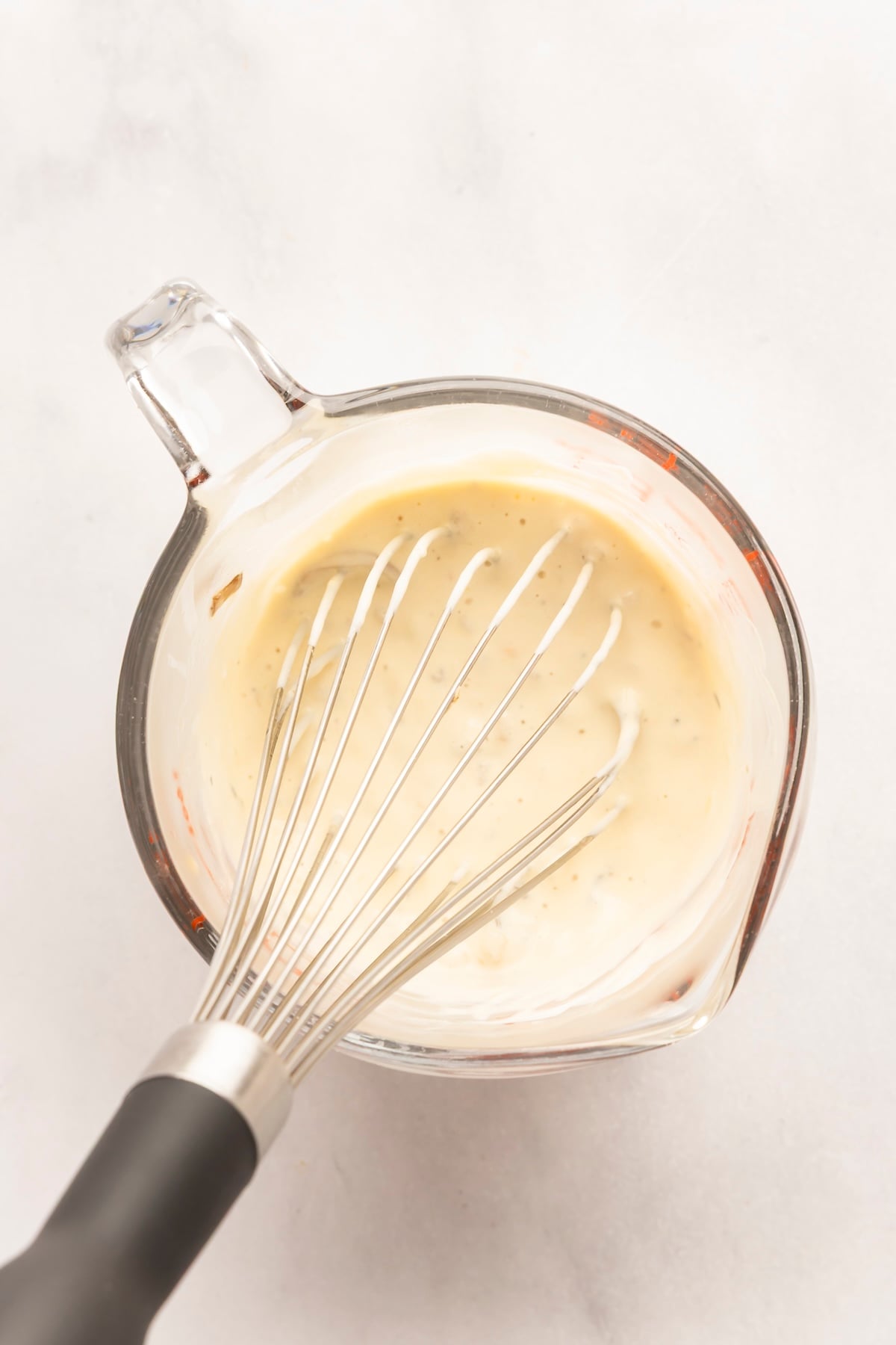 measuring cup with sour cream combined with ladleful of hot soup