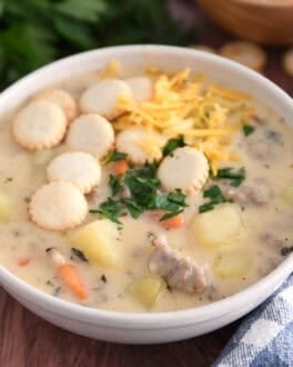 Soup bowl with sausage potato soup topped with oyster saltine crackers, fresh parsley and grated cheese.
