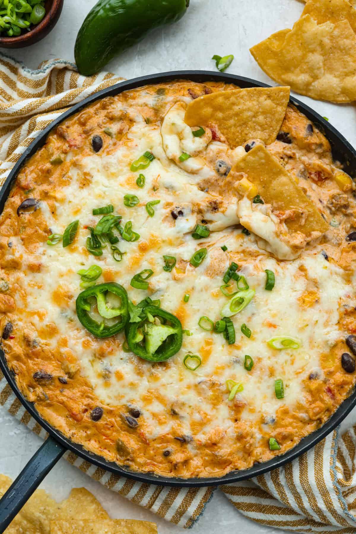 Hot cowboy dip garnished with green onions, jalapeño slices and a couple of tortilla chips.