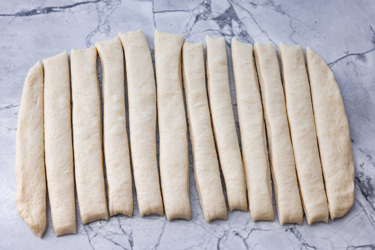 Dough shaped and spread out and sliced into breadstick shapes. 