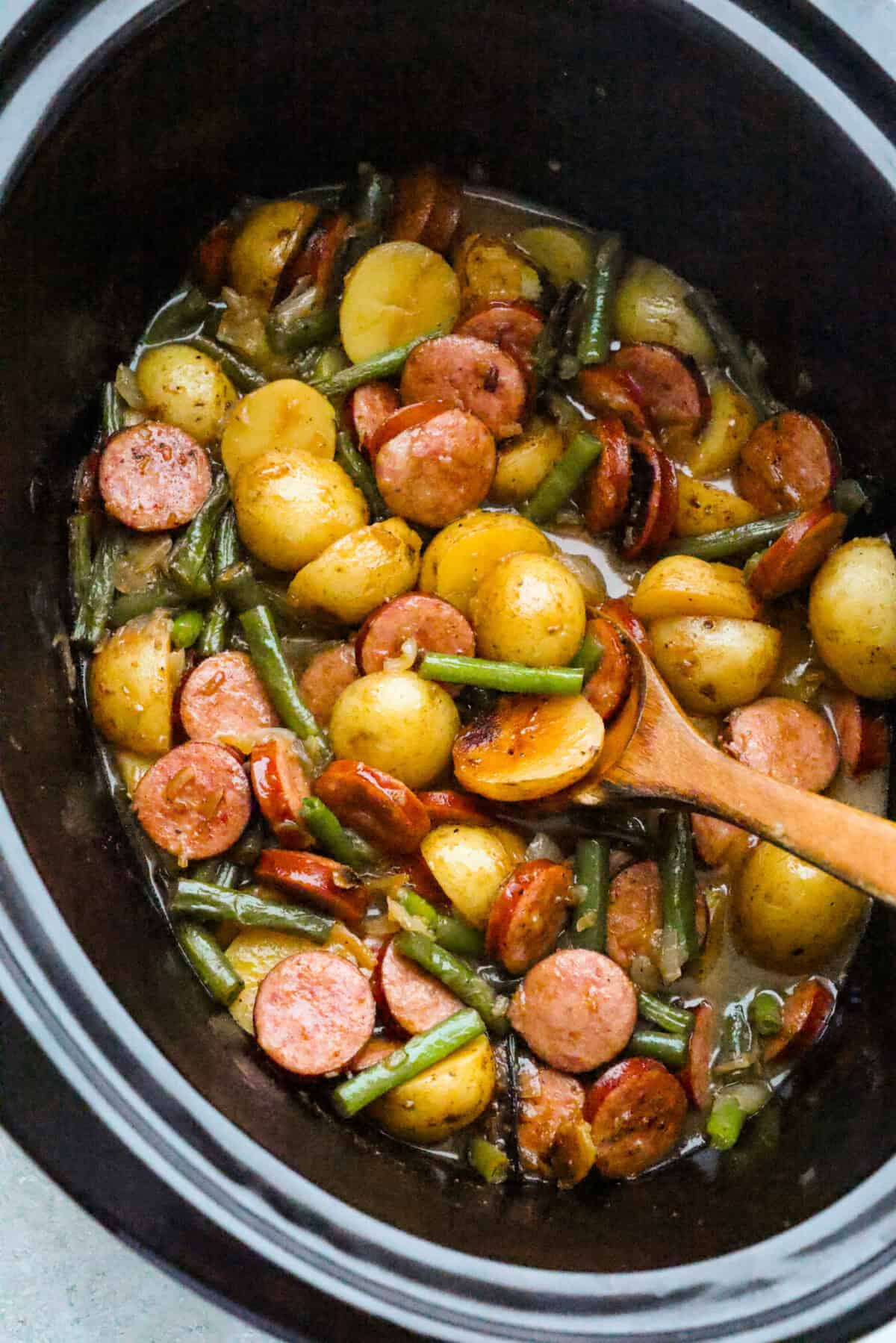 Slow cooker with cooked and ready to eat swamp potatoes with butter savory sauce and green beans.