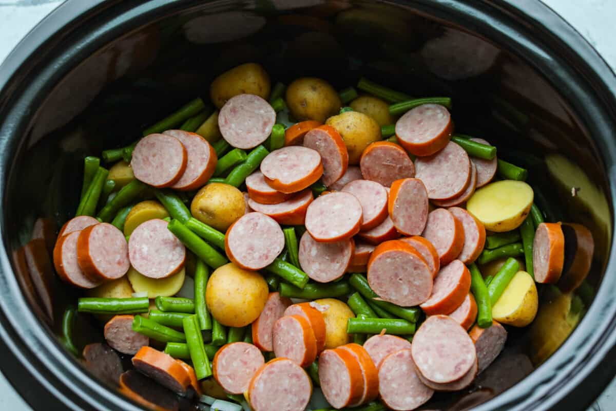 Sausage and vegetables cut up and added to the slow cooker. 