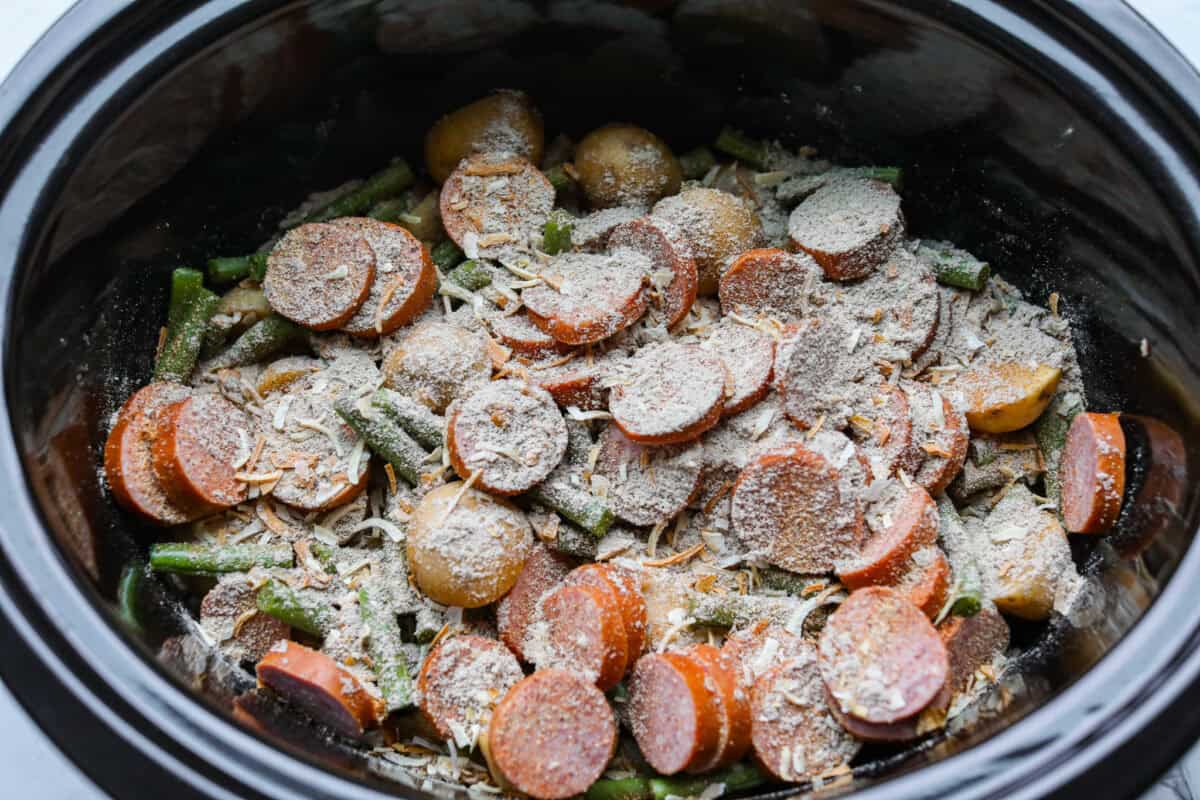 Seasonings added to the top of the ingredients in the slow cooker. 
