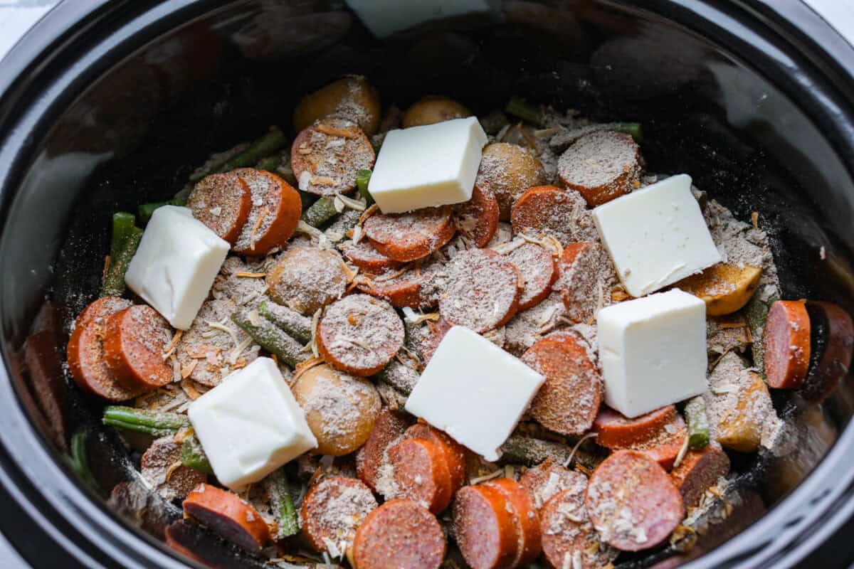 Cubes of butter added to the top of the seasonings on the other ingredients in the slow cooker. 