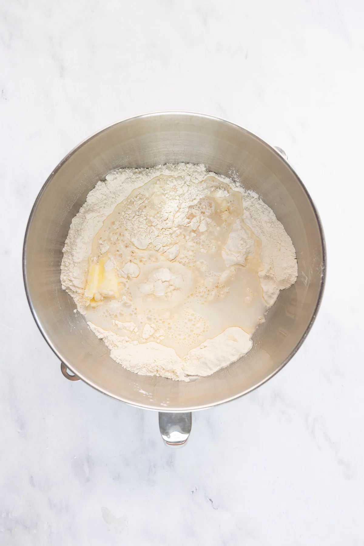 mixing bowl with butter, water, milk, and egg added to flour mixture