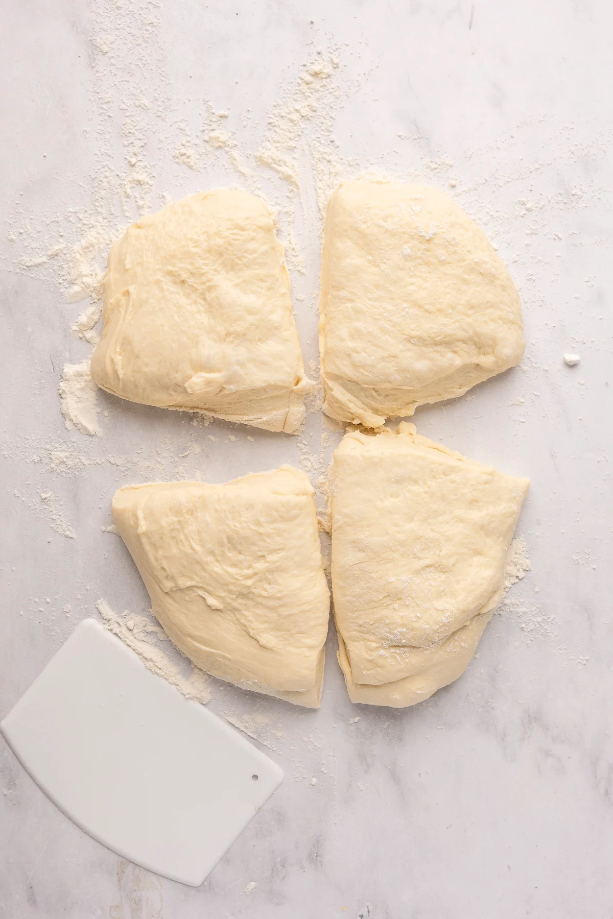 english muffin dough in in four portions on flour dusted surface