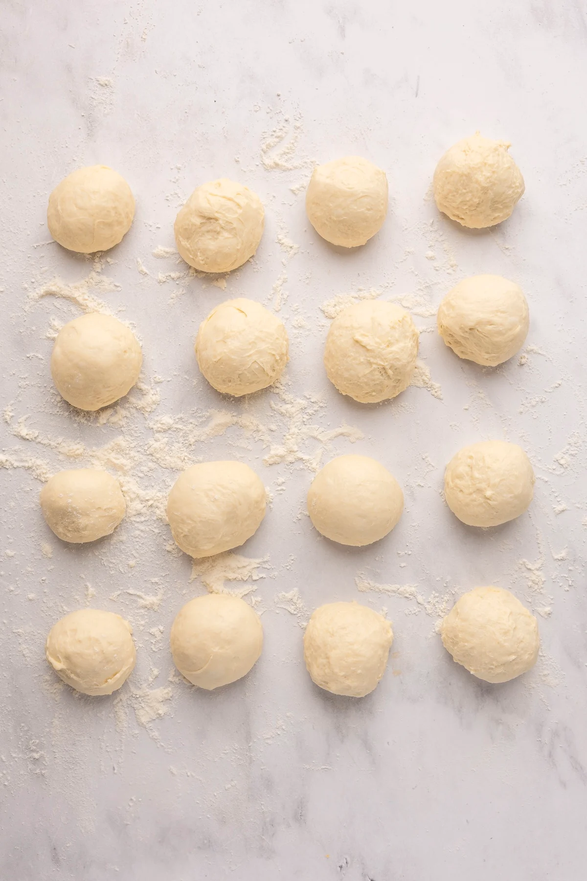 english muffin dough rolled into 16 balls on flour dusted surface