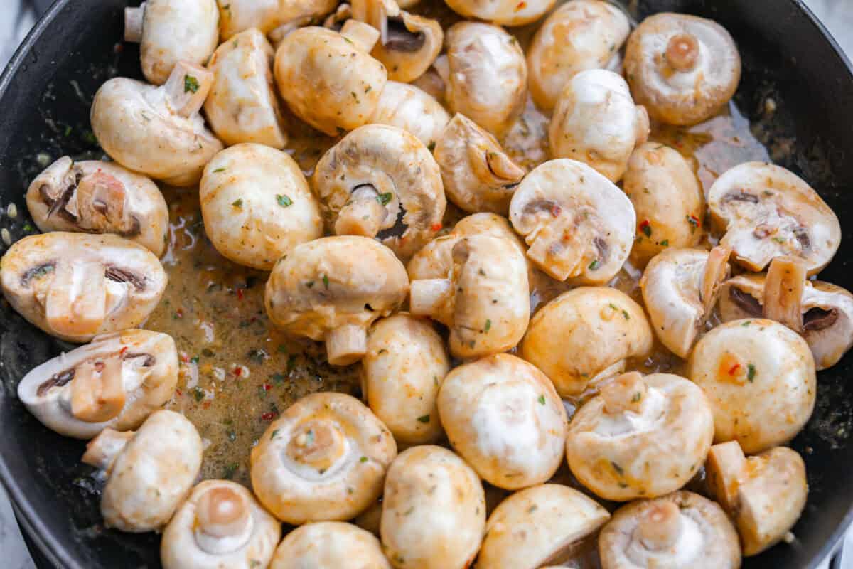 Button mushrooms added to the melted butter in the skillet.