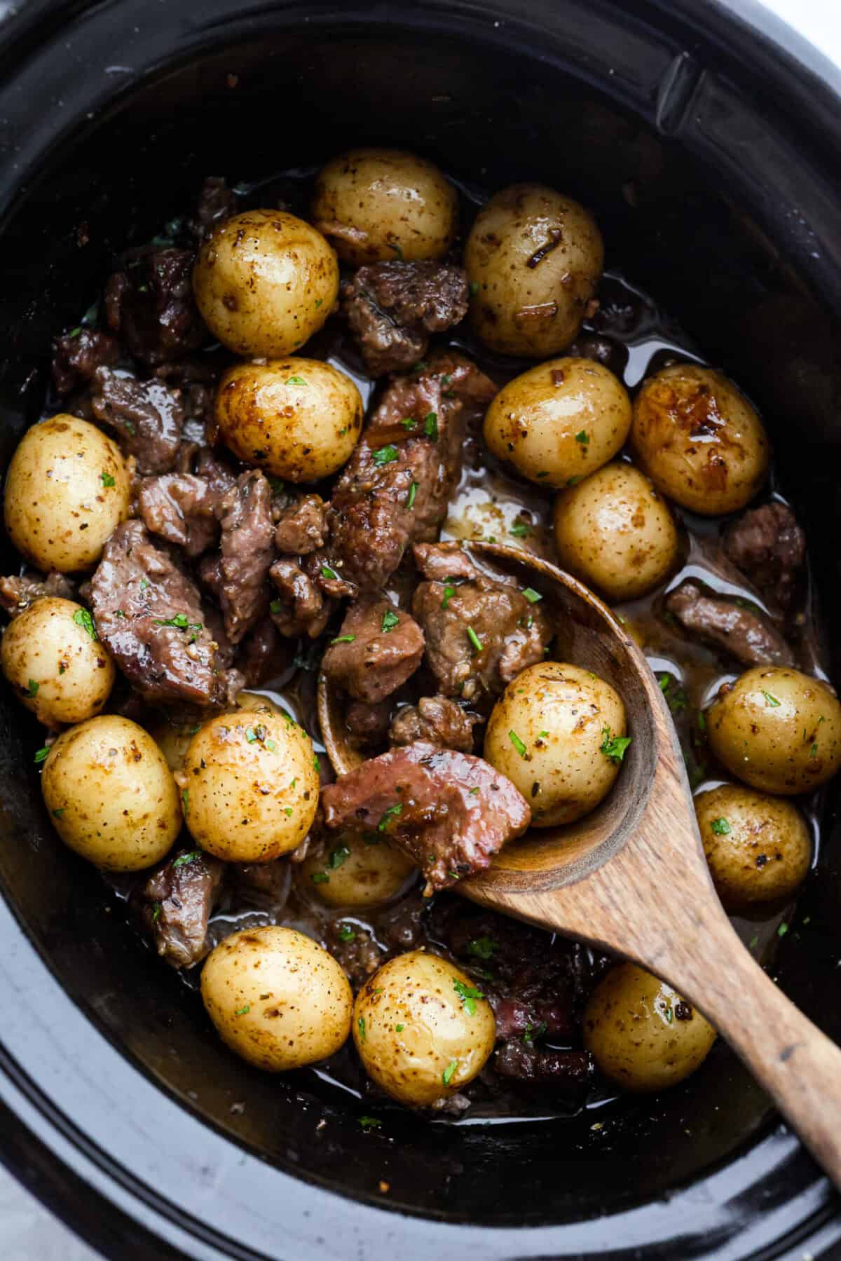 Slow cooker full of tender steak and potatoes smothered in a savory gravy sauce. 
